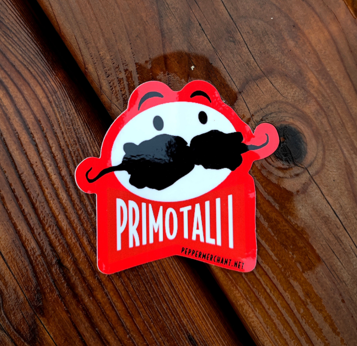 The Primotalii Sticker by PepperMerchant.net features a red and white cartoon face with mustache and "PRIMOTALII" text. Great for sticker fans, it displays peppermerchant.net and hints at larger PM seed packs available.
