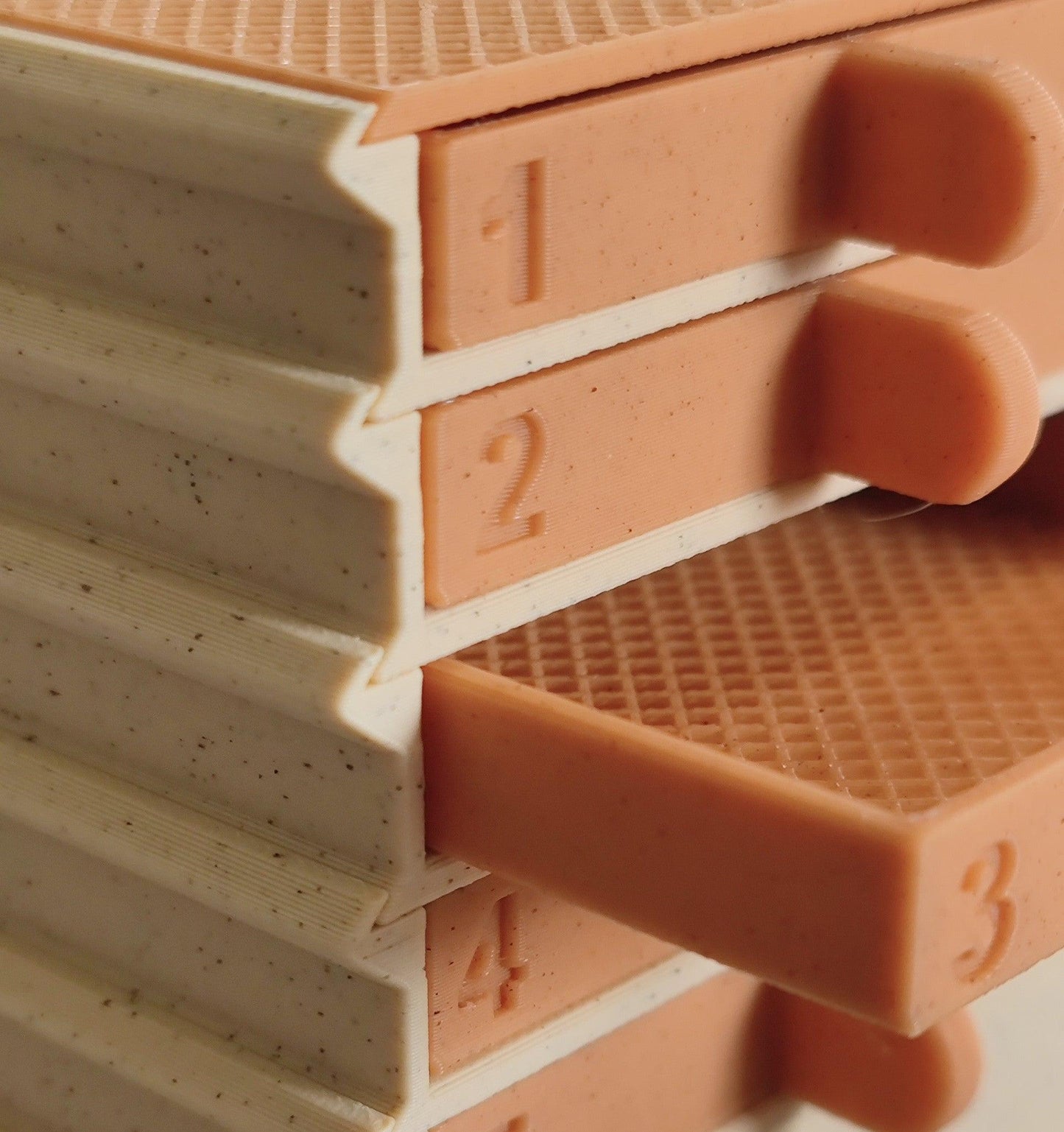 Close-up of a stack of beige and pink rectangular objects with textured surfaces and protruding tabs. Each tab is numbered in ascending order from 1 to 4. The pink objects, part of the PepperMerchant.net Seed Dryer - Pumpkin Spicy *Limited Edition only 8 Made*, are partially pulled out, revealing the textured layers underneath.