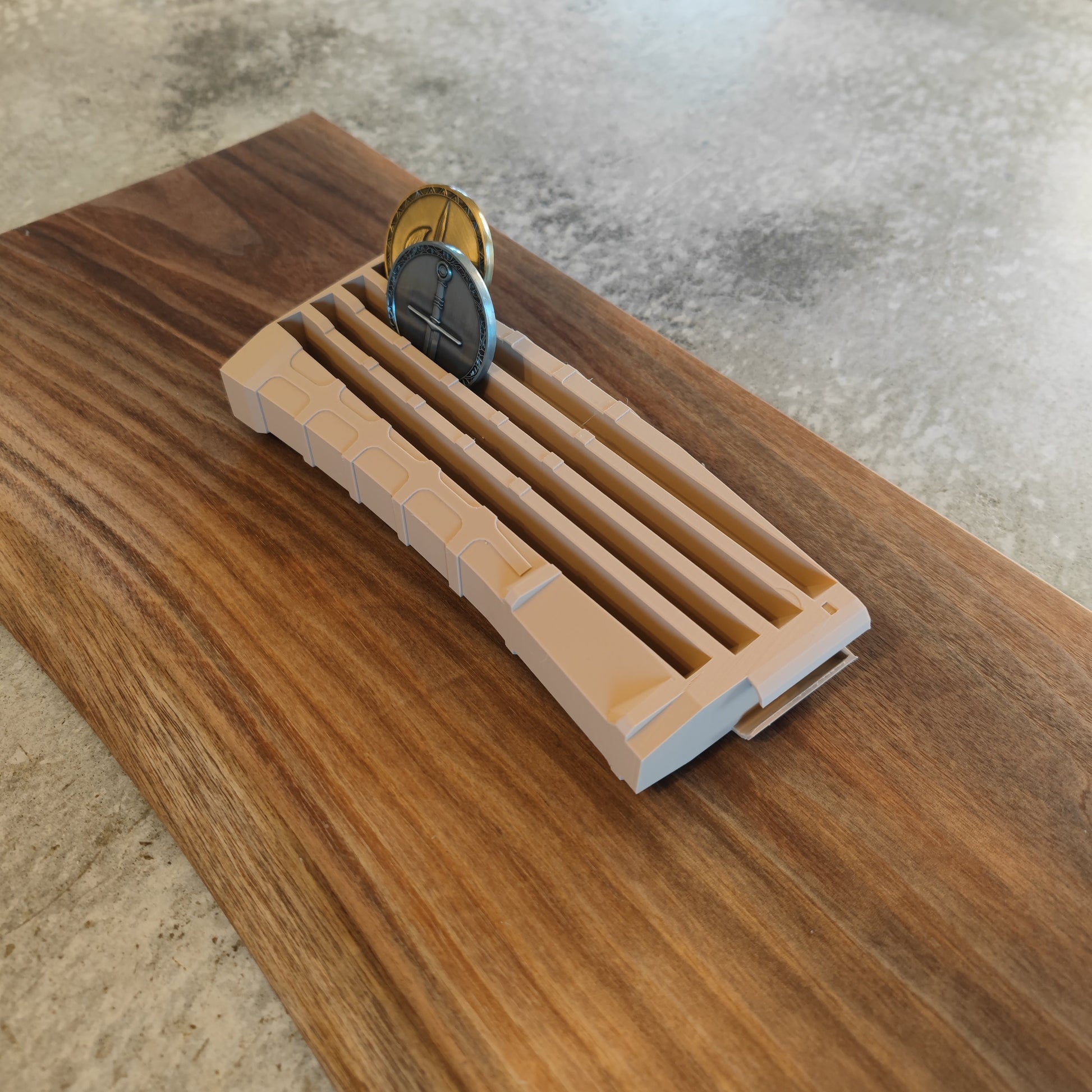 The GEN4 CoinMag - Sand by coin-mag.net is a compact plastic holder with grooves, displaying two coins upright on a wooden surface against a gray textured background.