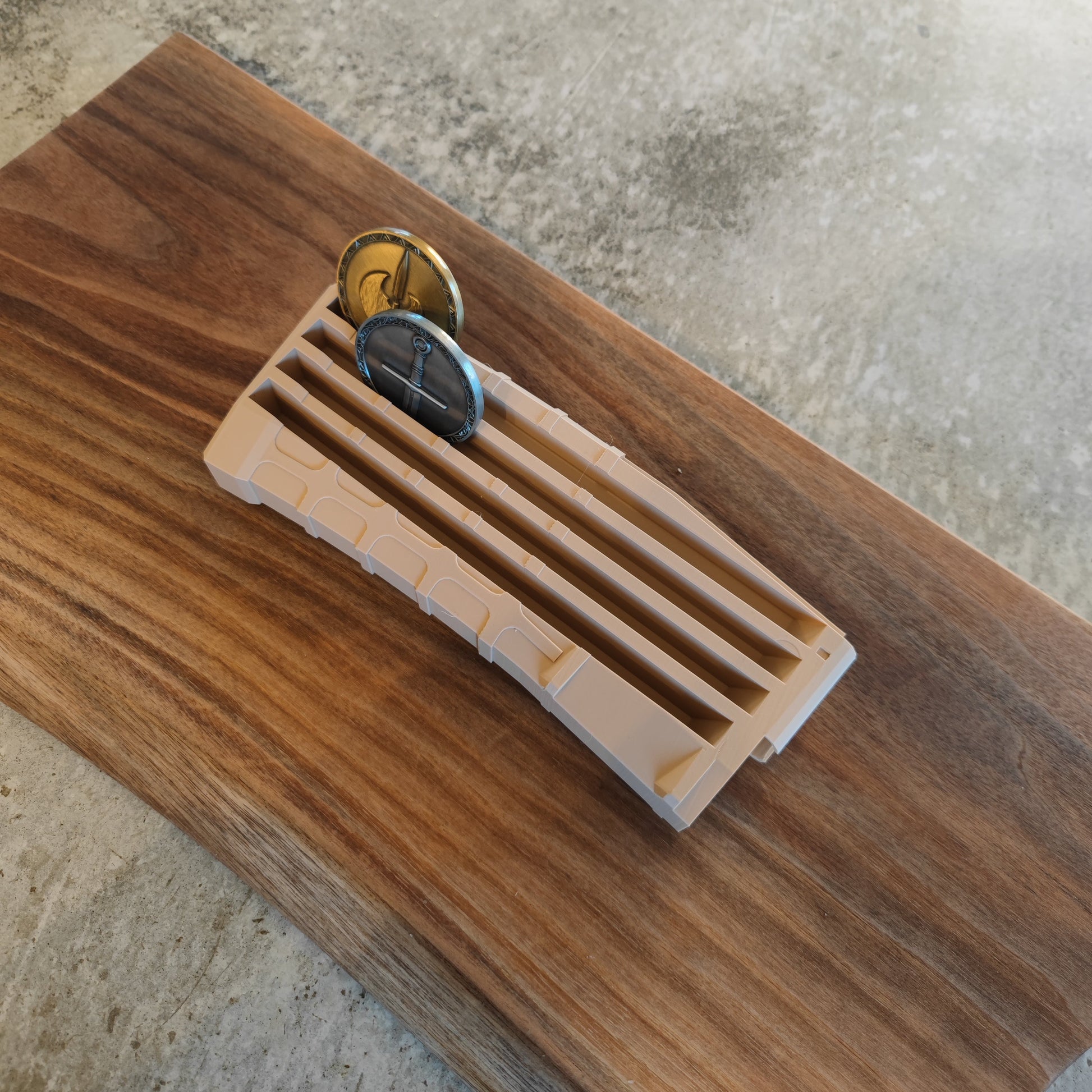 The GEN4 CoinMag - Sand by coin-mag.net is a beige plastic holder with slots and two circular metal blades, shown on a wooden cutting board over a concrete surface.