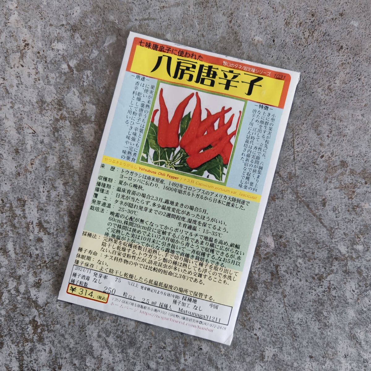 A packet of Yatsufusa (Yatzy) chili pepper seeds, featuring a photograph of red peppers and detailed cultivation instructions in Japanese.