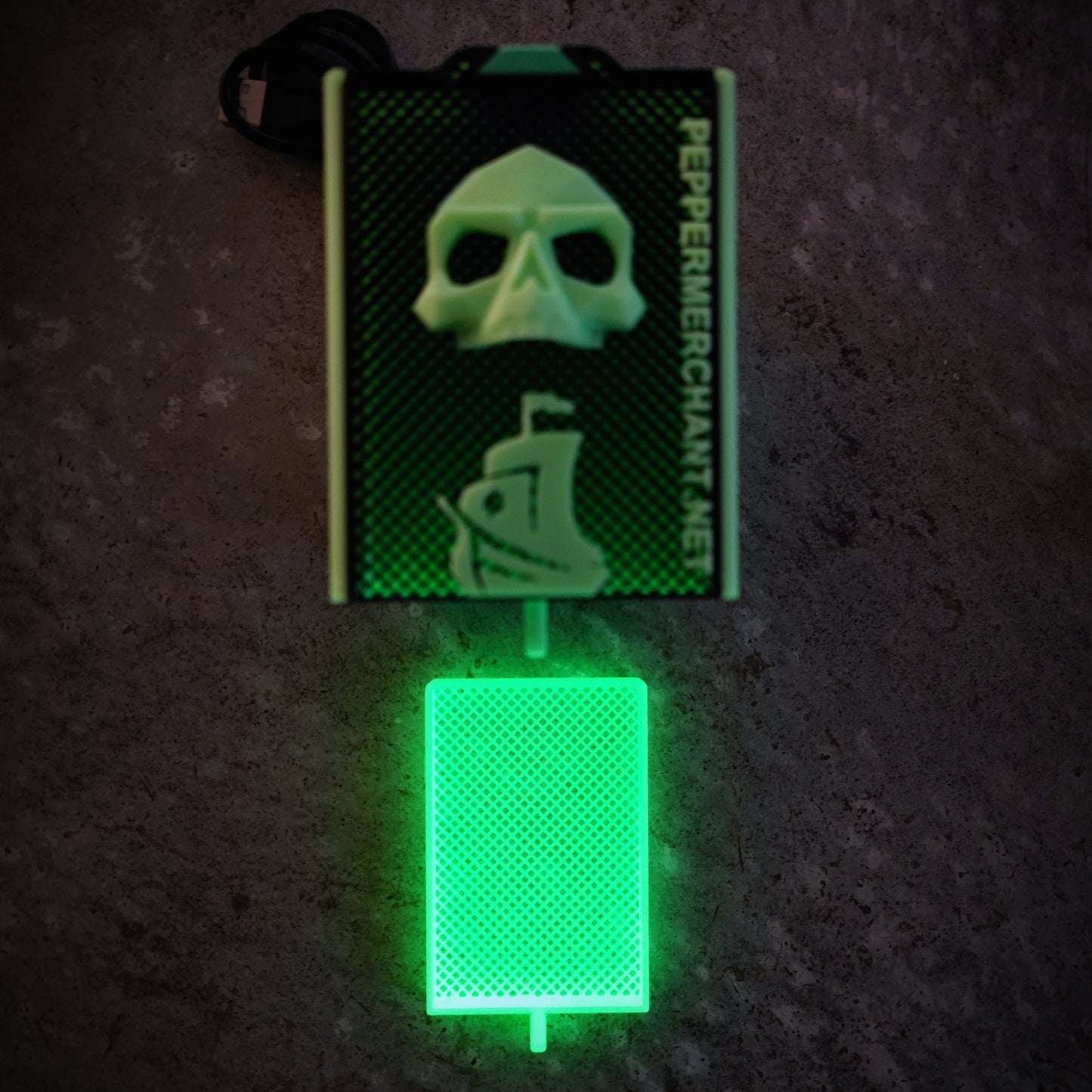 The Seed Dryer - Limited Glowing Edition by PepperMerchant.net features a green LED-lit card reader with a skull and pirate ship design, textured surface, glowing card slot, and "PepperMerchant.net" printed vertically.