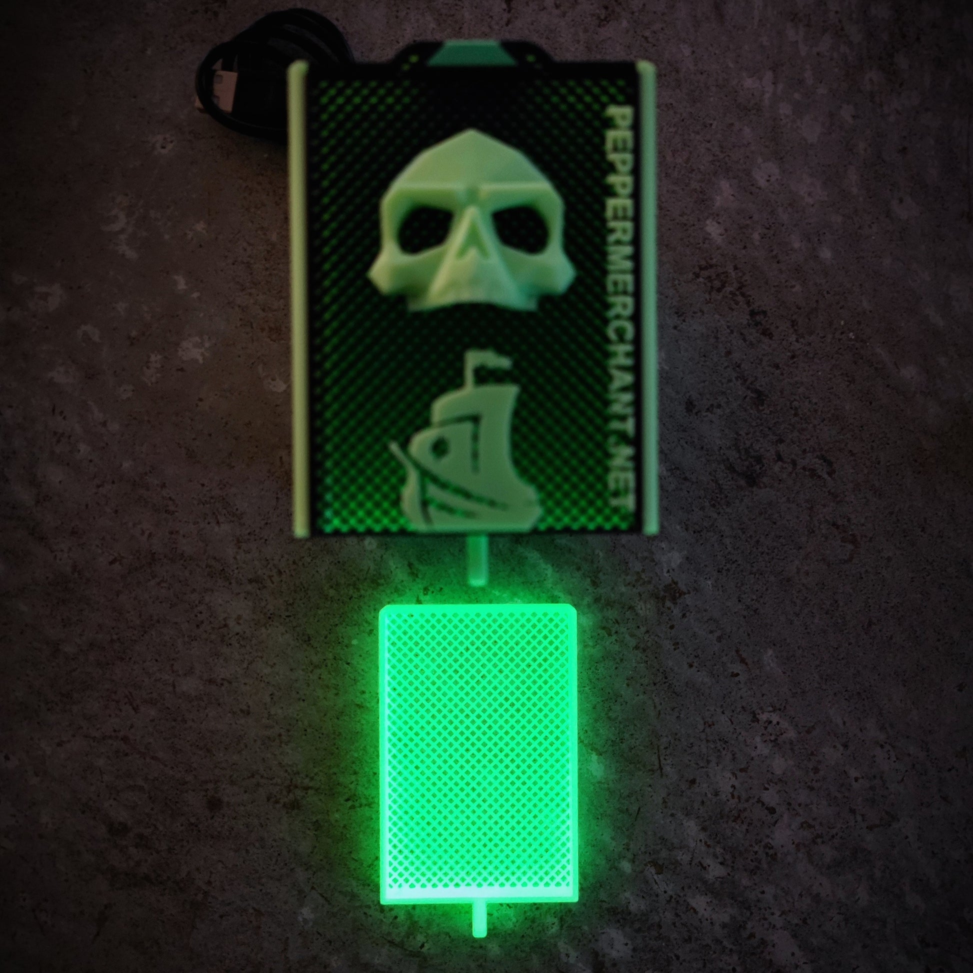 The Seed Dryer - Limited Glowing Edition by PepperMerchant.net features a green LED-lit card reader with a skull and pirate ship design, textured surface, glowing card slot, and "PepperMerchant.net" printed vertically.